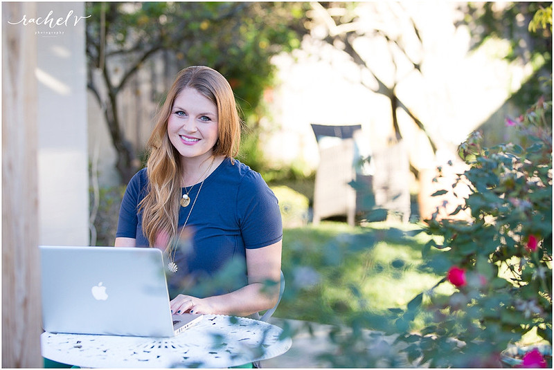 Woman in blue shirt sitting outdoors and working on an apple computer
