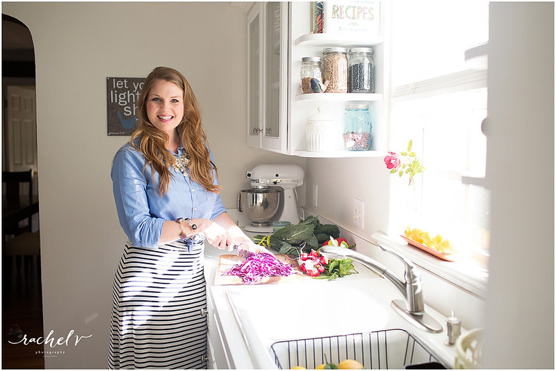 Woman in blue shirt chopping veggies in a brightly lit kitchen
